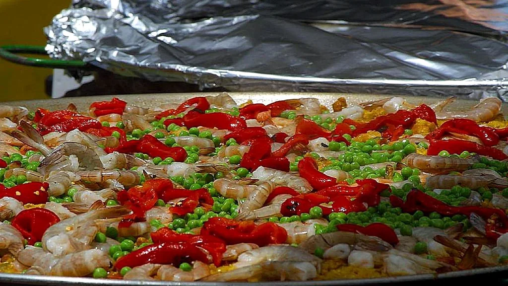 Grande padella con riso, gamberi, piselli e peperoni durante la preparazione