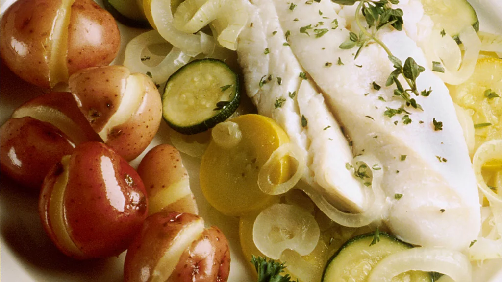 Pesce intero cotto al forno con verdure ed erbe in una pirofila