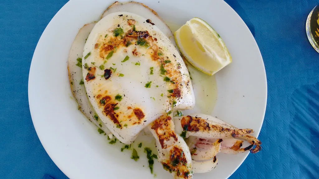 Seppia alla piastra con superficie dorata e segni di rosolatura su corpo e tentacoli