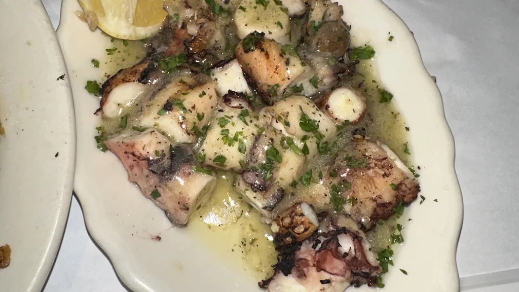Polpo grigliato con zone rosolate, servito con limone e prezzemolo